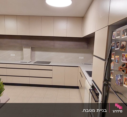 מטבח מודרני עם ארונות בהירים ומקרר עם מגנטים